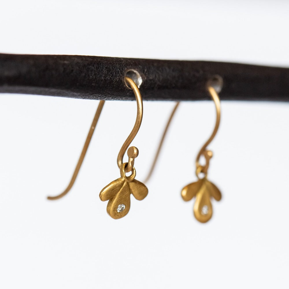 Tiny gold leaf-like drop earrings are accented by tiny diamonds.
