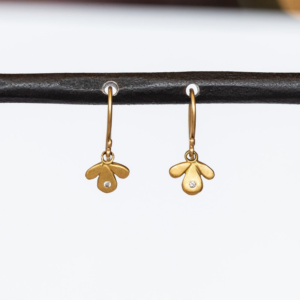 Tiny gold leaf-like drop earrings are accented by tiny diamonds.