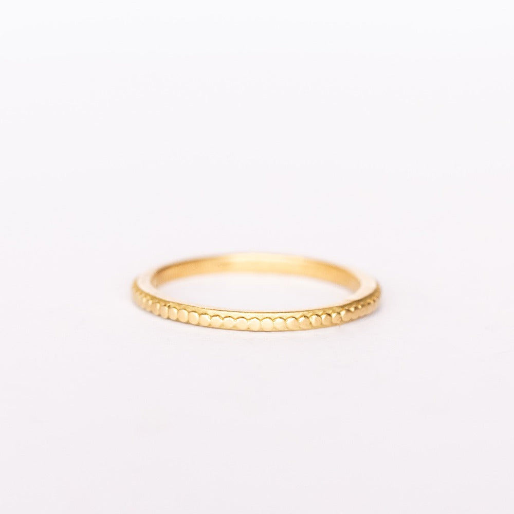 A yellow gold band with a tiny raised dot pattern from Ananda Khalsa. Front view.