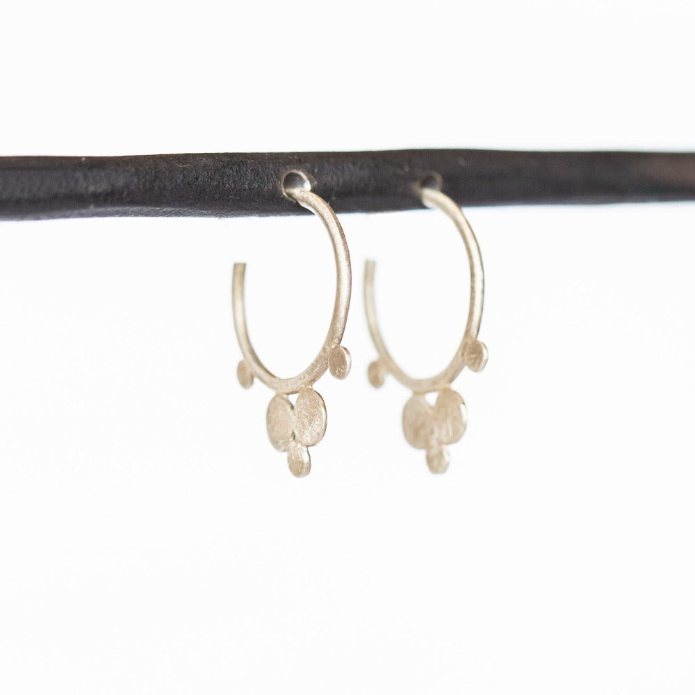 A pair of petite, brushed silver hoop earrings that feature flat dot accents.