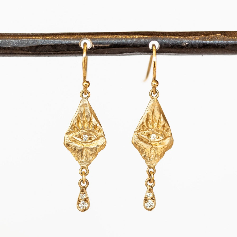 Gold diamond-shaped drop earrings with hand carved eye designs and diamond drops.