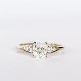 A diamond engagement ring with an old mine cushion cut center stone, raised cathedral shoulders with accent diamonds, in 18k white gold.