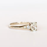 A diamond engagement ring with an old mine cushion cut center stone, raised cathedral shoulders with accent diamonds, in 18k white gold.