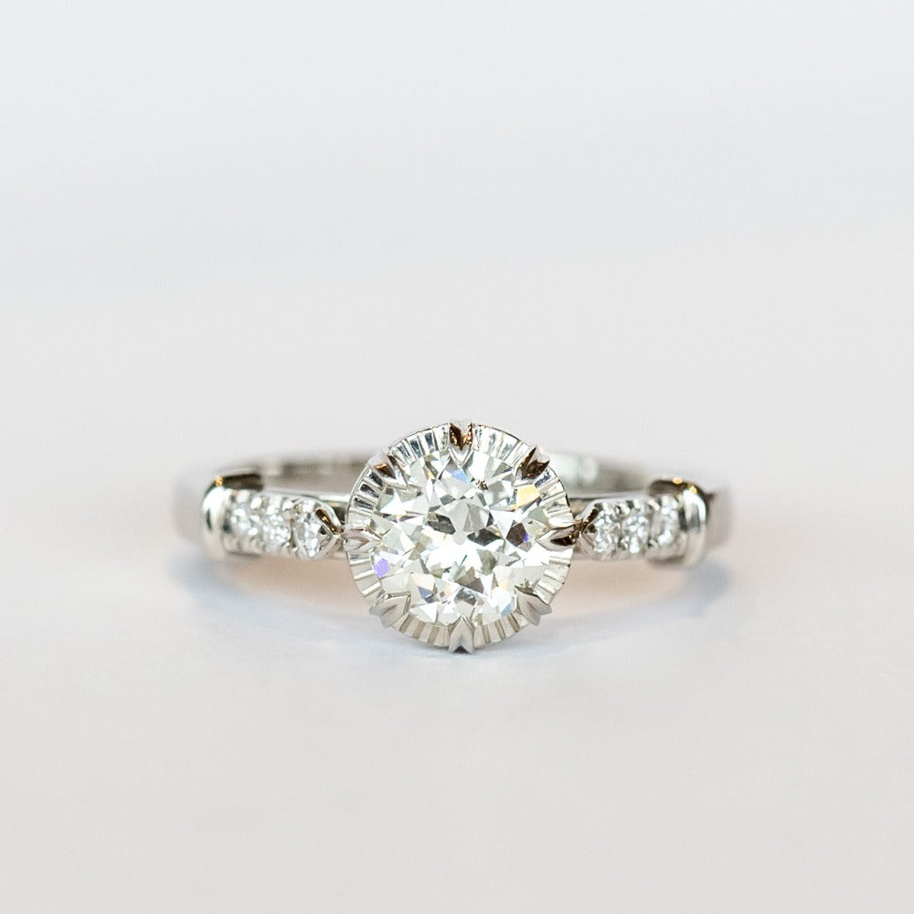 A platinum engagement ring with a prong set old European cut diamond, cathedral shoulders, and three accent diamonds on each shoulder.