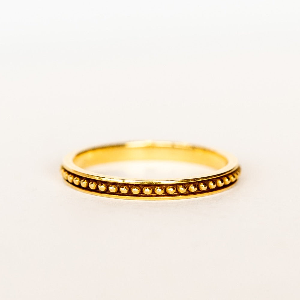 A rose gold wedding band with beaded detail all the way around and oxidized surface for contrast.