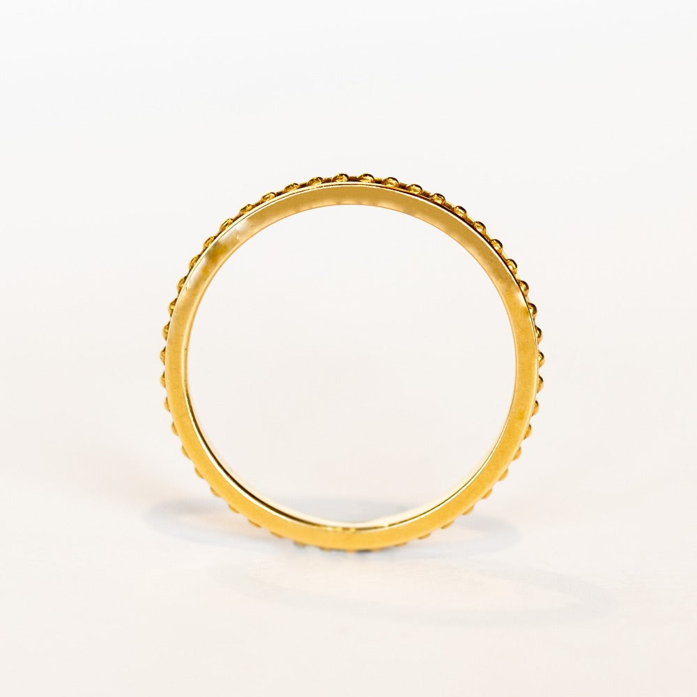 A rose gold wedding band with beaded detail all the way around and oxidized surface for contrast.