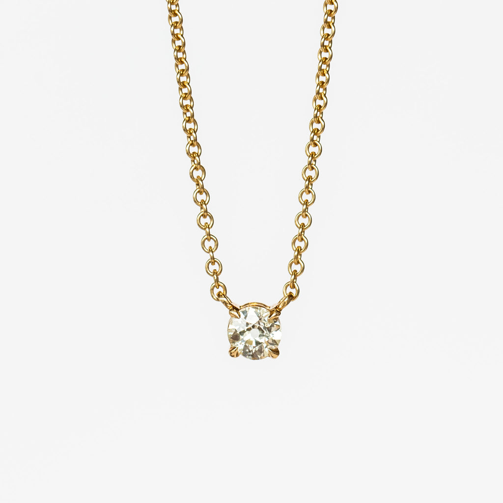 A prong set old mine cut diamond station pendant on a yellow gold cable chain necklace.