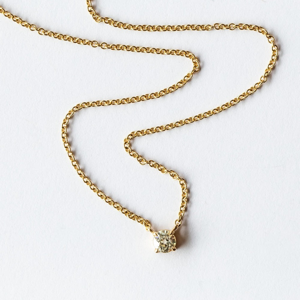 A prong set old mine cut diamond station pendant on a yellow gold cable chain necklace.