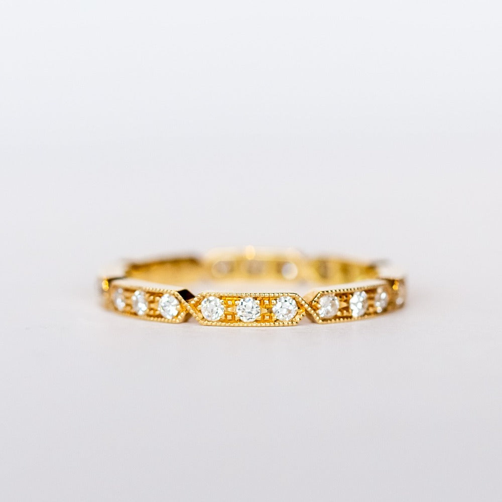 A yellow gold diamond eternty ring with notched edges and milgrain detials.