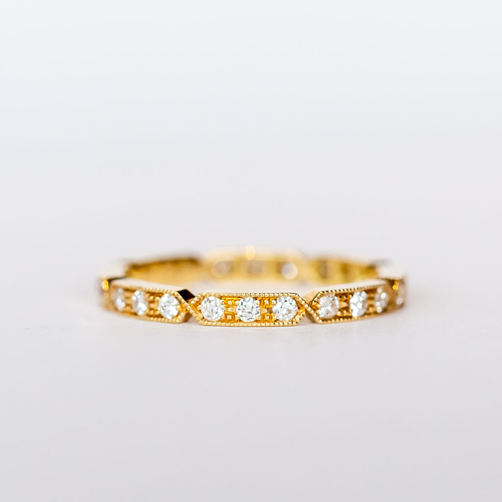 A yellow gold diamond eternty ring with notched edges and milgrain detials.
