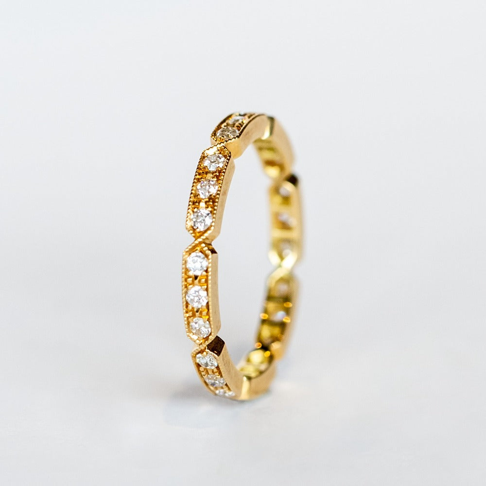 A yellow gold diamond eternty ring with notched edges and milgrain detials.
