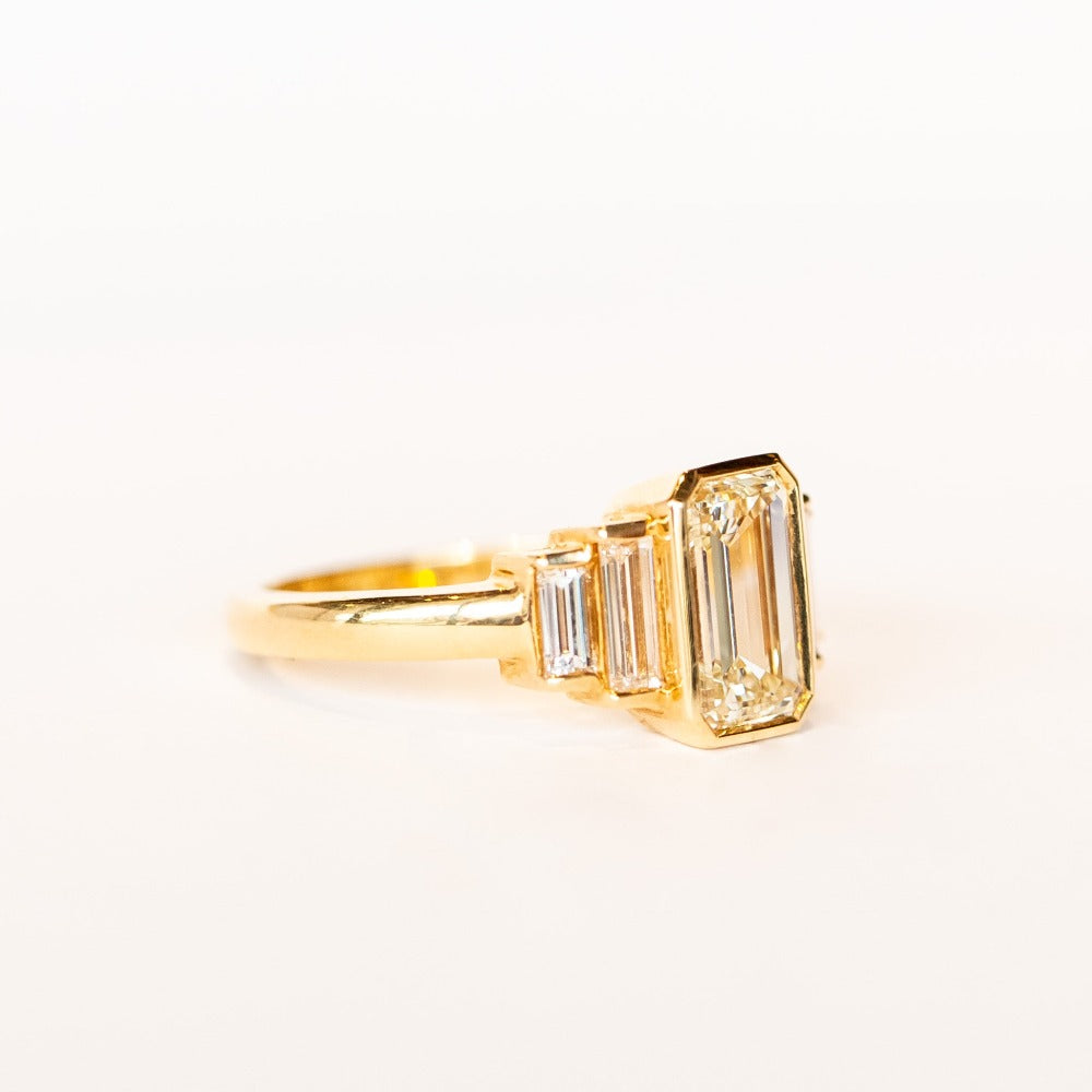 A yellow gold, emerald cut diamond engagement ring with baguette cut side stones.