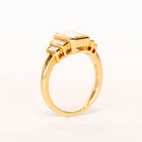 A yellow gold, emerald cut diamond engagement ring with baguette cut side stones.