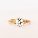 An old European cut diamond engagement ring in yellow gold with filigree accents and several side stones set into the shoulders.