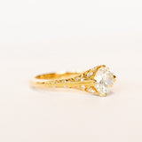 An old European cut diamond engagement ring in yellow gold with filigree accents and several side stones set into the shoulders.
