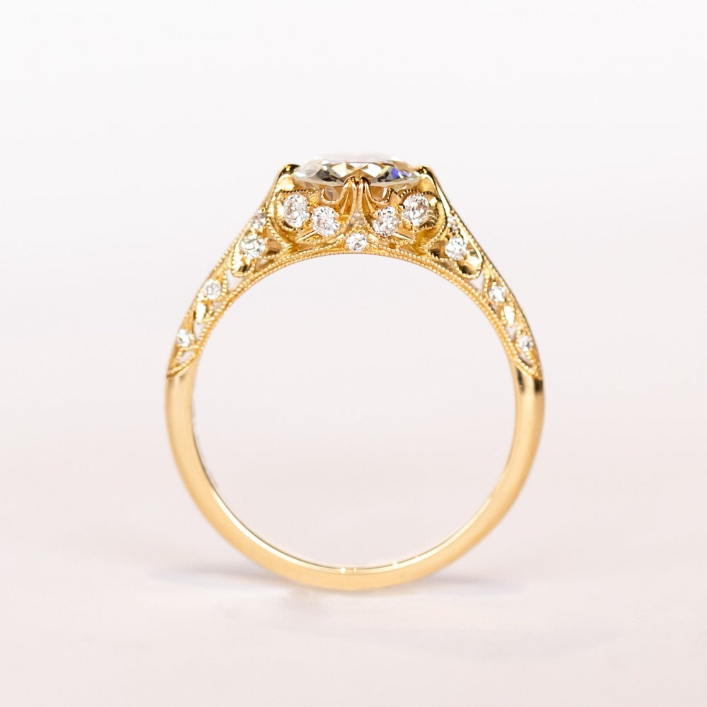 An old European cut diamond engagement ring in yellow gold with filigree accents and several side stones set into the shoulders.
