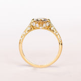An old European cut diamond engagement ring in yellow gold with filigree accents and several side stones set into the shoulders.