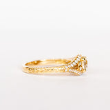 A yellow gold engagement ring that features an old European cut center diamond, floral filigree accents, and rows of pave diamonds.