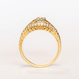 A yellow gold engagement ring that features an old European cut center diamond, floral filigree accents, and rows of pave diamonds.