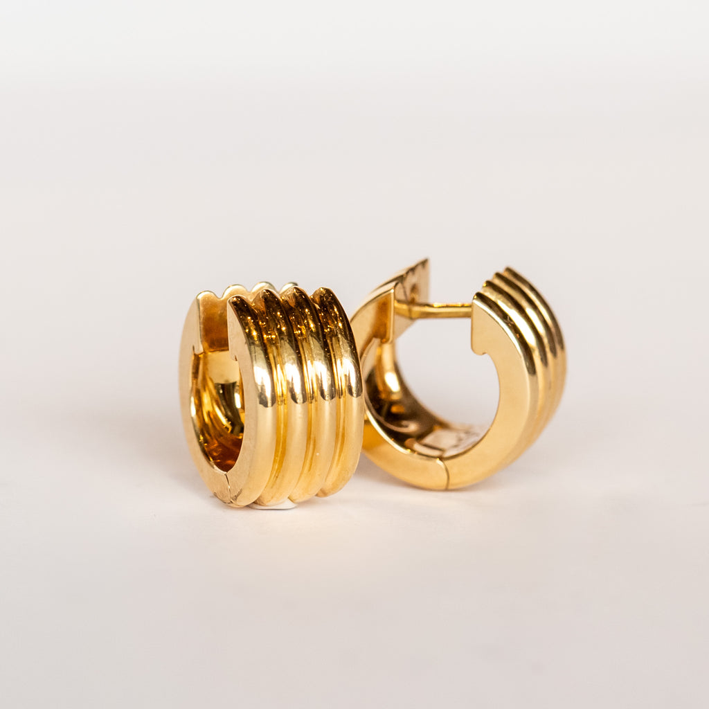 Yellow gold wide huggie hoop earrings with a ribbed texture.