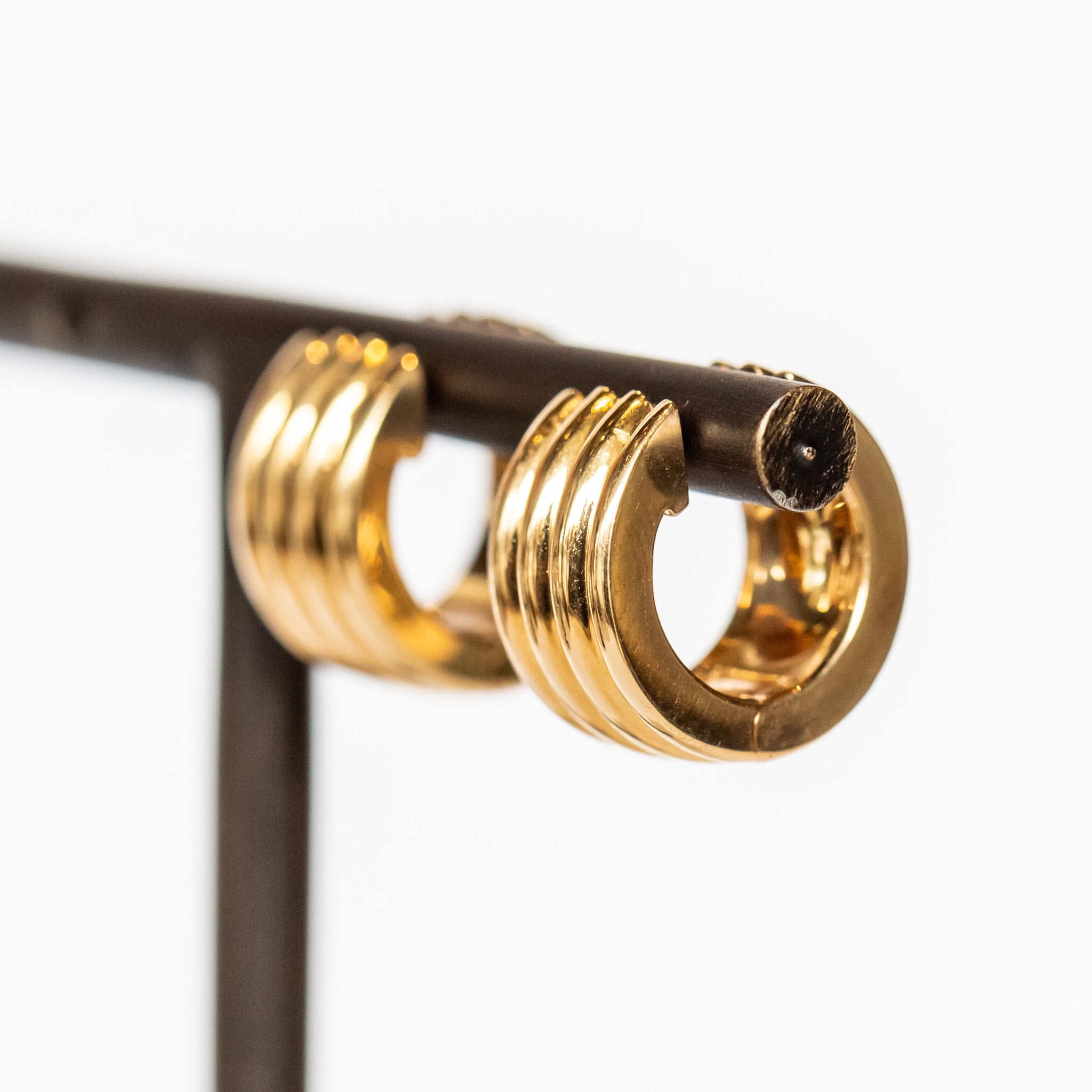 Yellow gold wide huggie hoop earrings with a ribbed texture.
