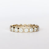 A white gold and diamond eternity band with bezel set old European cut diamonds and milgrain accents.