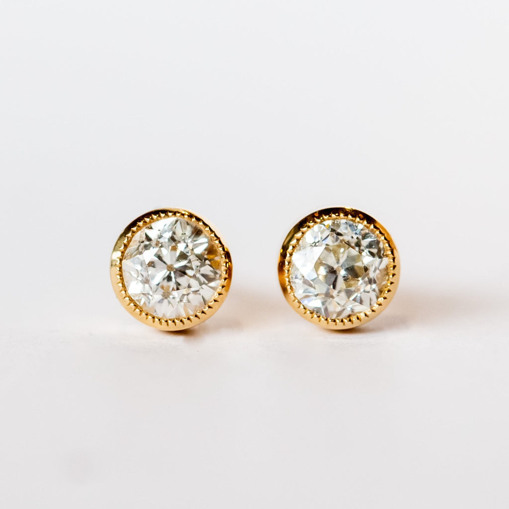Old European cut diamond stud earrings set in yellow gold bezels with milgrain edges.