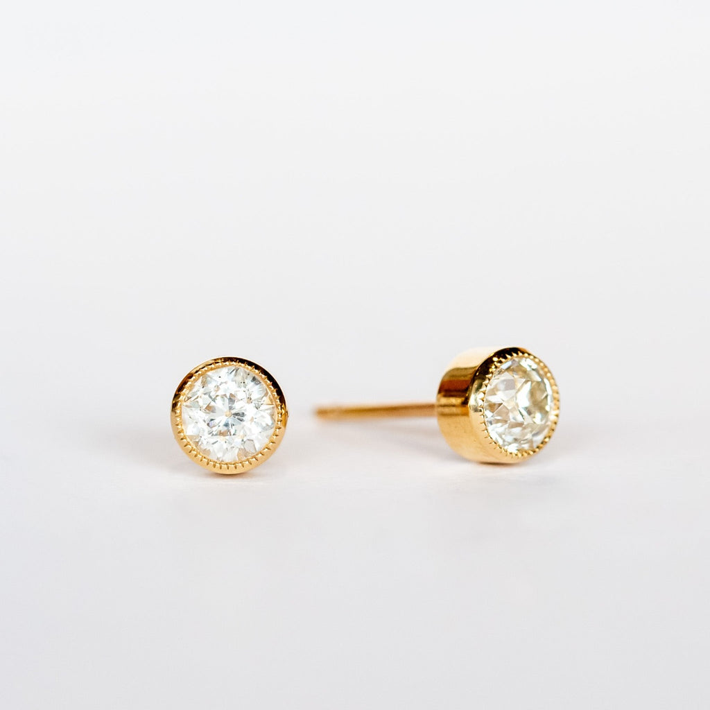 Old European cut diamond stud earrings set in yellow gold bezels with milgrain edges.