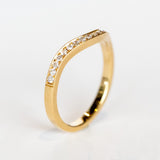 A contour curved yellow gold wedding band with a row of petite diamonds along the top.