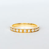 A yellow gold wedding band with a row of round old European cut diamonds, pave set around half of the band, with milgrain accents on each side and in between in a square pattern.