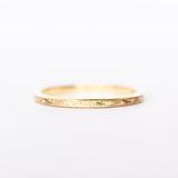 A thin, engraved yellow gold wedding band.