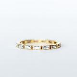 A yellow gold eternity band made up of bezel set, rectangular French cut diamonds.