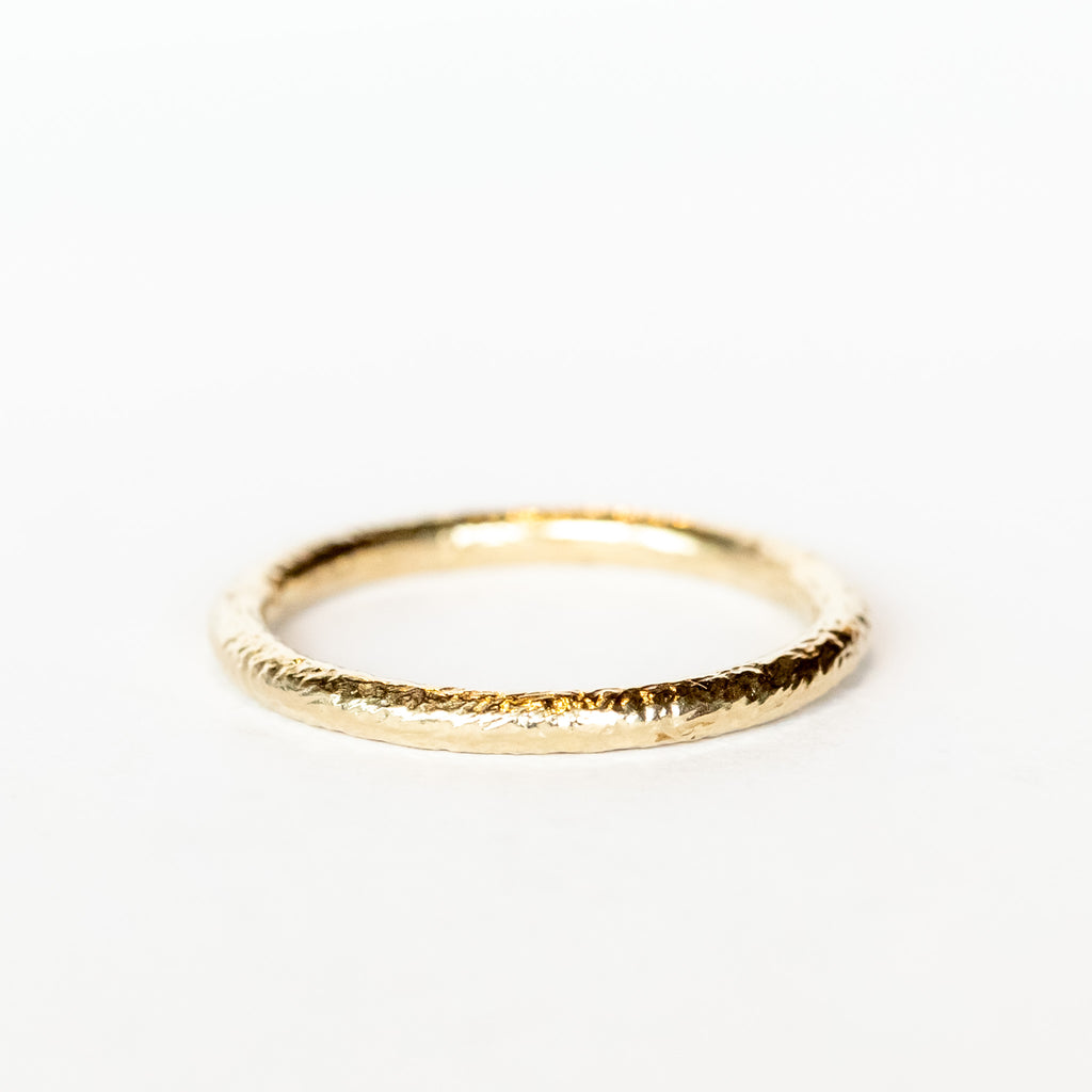 A thin champagne gold wedding band with hammered texture.