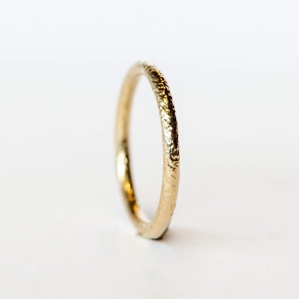 A thin champagne gold wedding band with hammered texture.