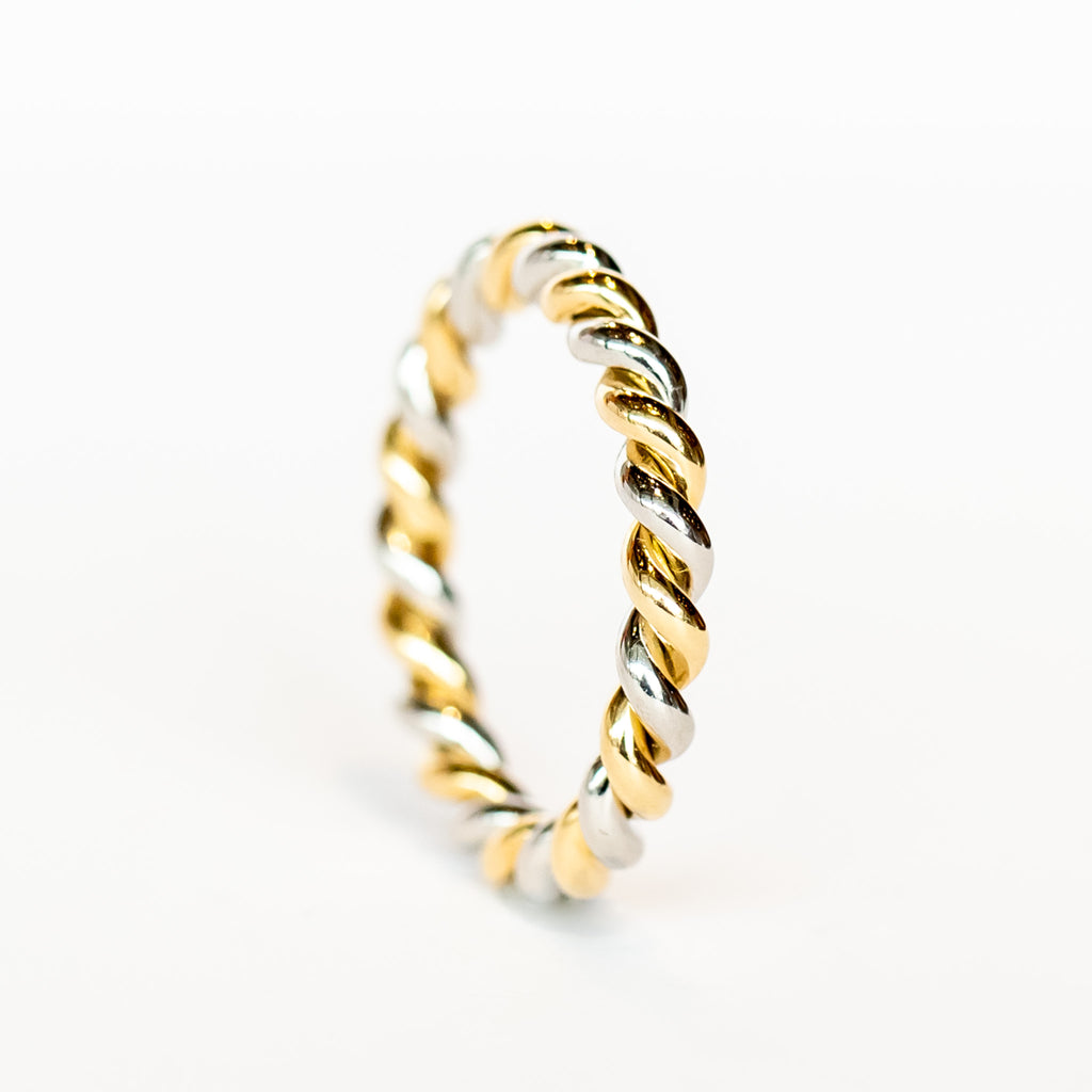 A wedding band made up of one platinum and one yellow gold strands twisted together with a polished finish.