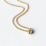 A bezel set cushion cut diamond in yellow gold on a cable chain necklace.