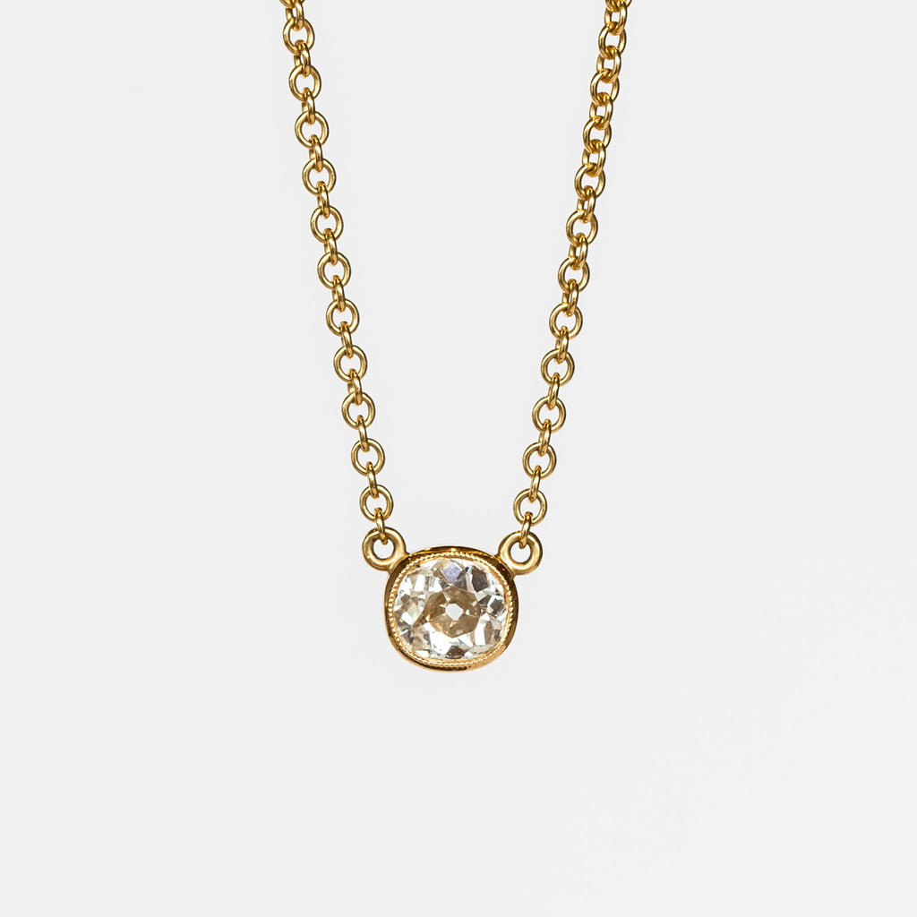 A bezel set cushion cut diamond in yellow gold on a cable chain necklace.