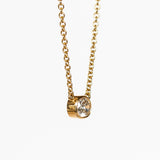 A bezel set cushion cut diamond in yellow gold on a cable chain necklace.