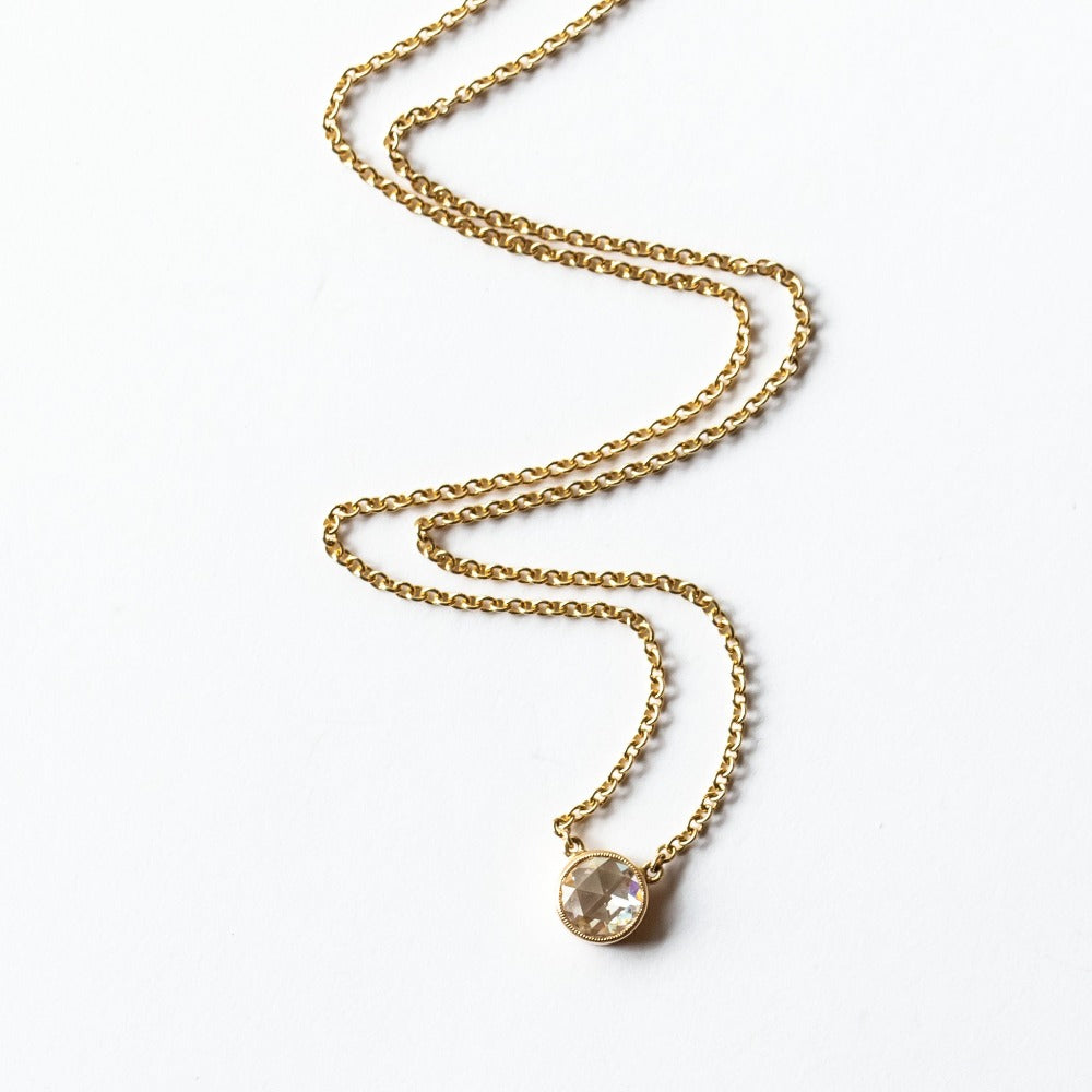 A round rose cut diamond bezel set in a station style necklace with classic gold cable chain.