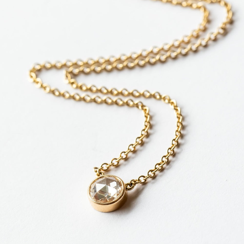 A round rose cut diamond bezel set in a station style necklace with classic gold cable chain.