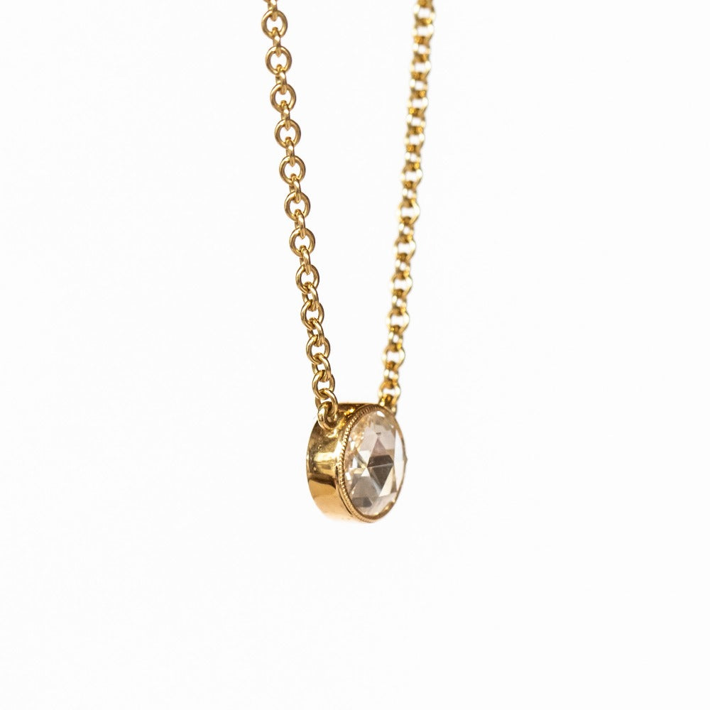 A round rose cut diamond bezel set in a station style necklace with classic gold cable chain.