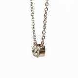 A cushion cut diamond in a platinum bezel setting with milgrain edge, stationed at the center of a platinum cable chain necklace.
