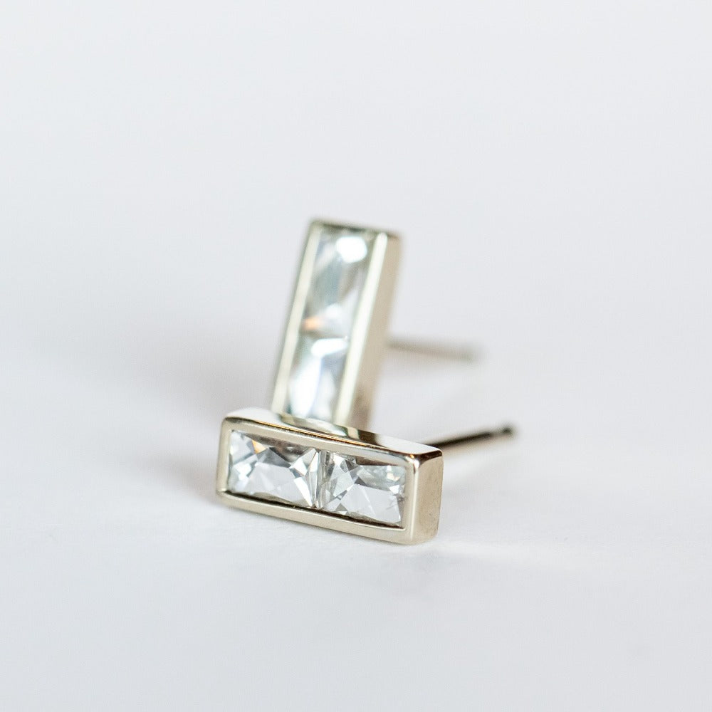 Diamond stud earrings featuring pairs of French cut diamonds bezel set in white gold with a post back.