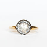 A round rose cut diamond in a sterling silver solitaire prong setting with a yellow gold band.