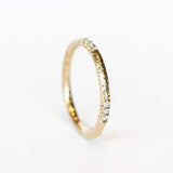 A white gold wedding band with a hammered texture and rows of three-diamonds inlaid in a spaced out design.
