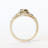 A vintage style diamond engagement ring with a bezel set center stone surrounded by an airy filigree setting and many other diamonds.