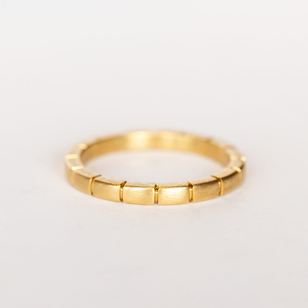 A brushed finish, yellow gold band with ridged details all the way around.