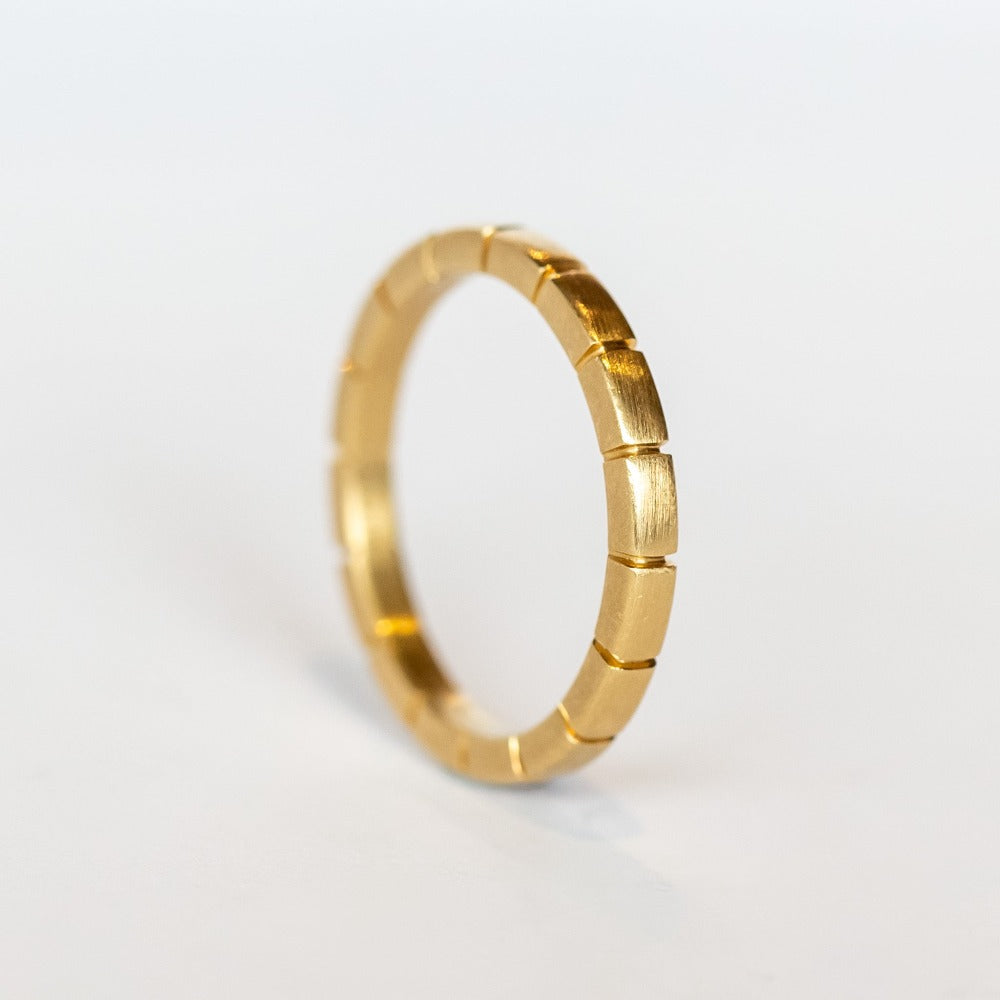 A brushed finish, yellow gold band with ridged details all the way around.