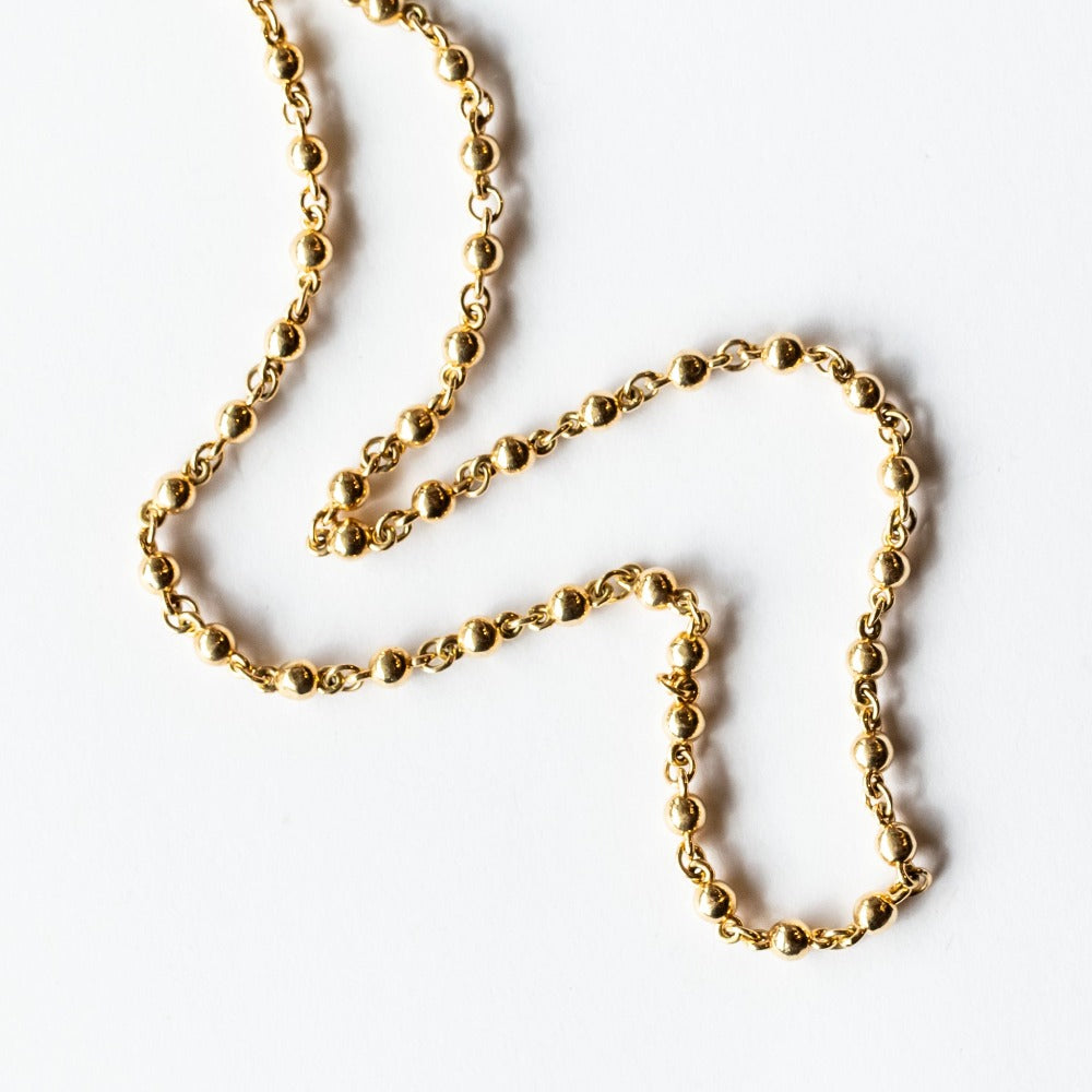 A yellow gold chain necklace made up of spherical links.
