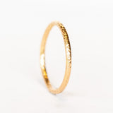 A thin, textured rose gold wedding band.